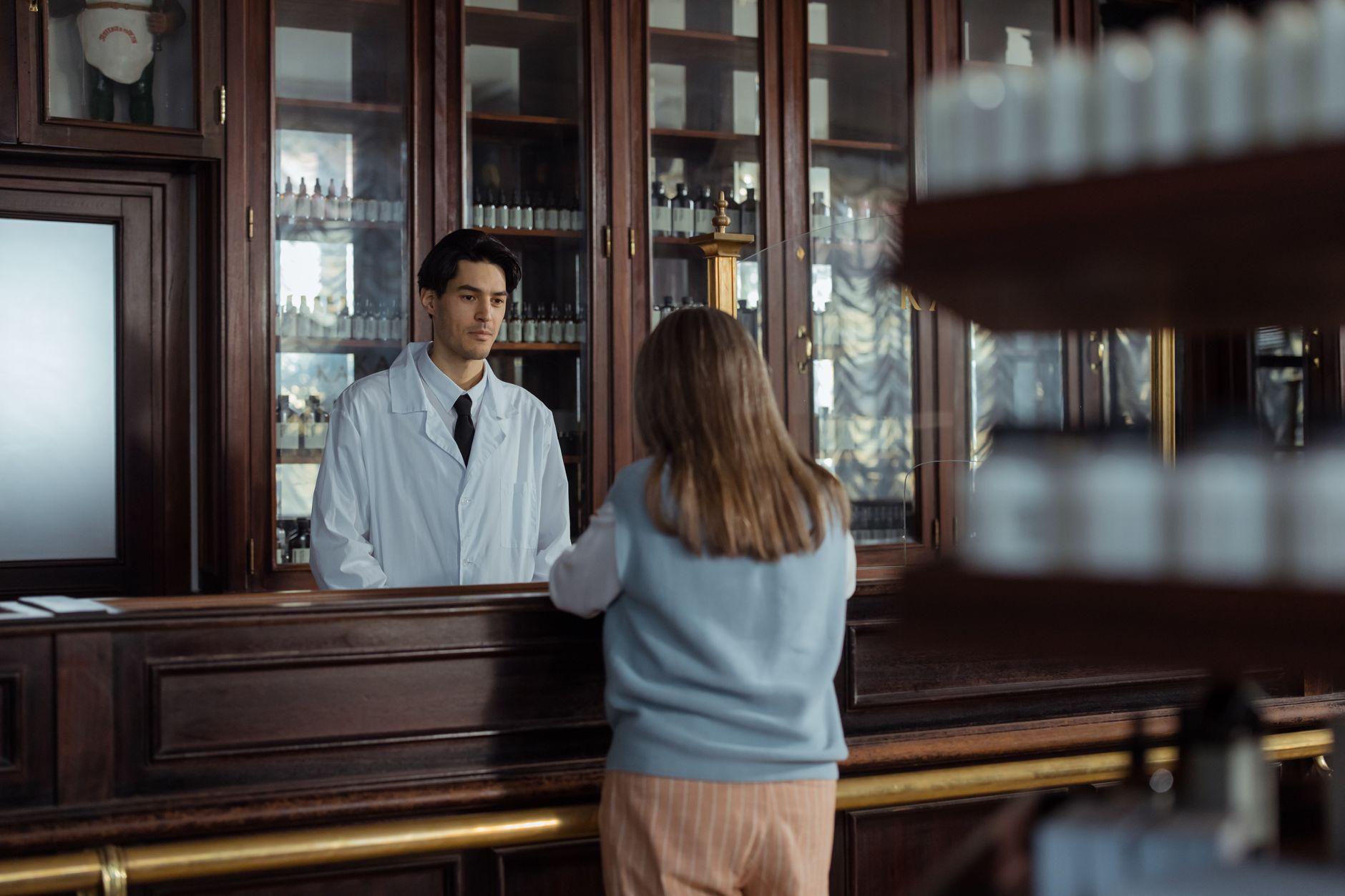 Pharmacist serving customer at pharmacy counter — mystery shopper audit