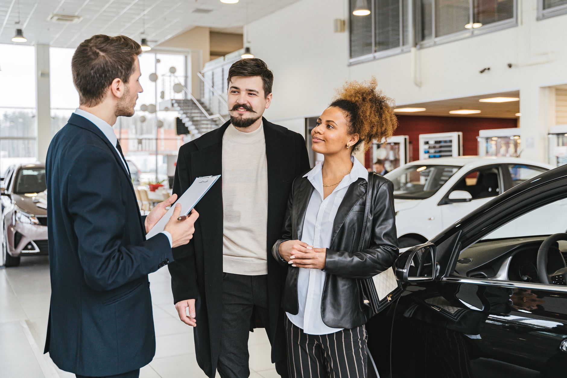 Vendedor de coches mostrando un vehículo a un cliente en el concesionario
