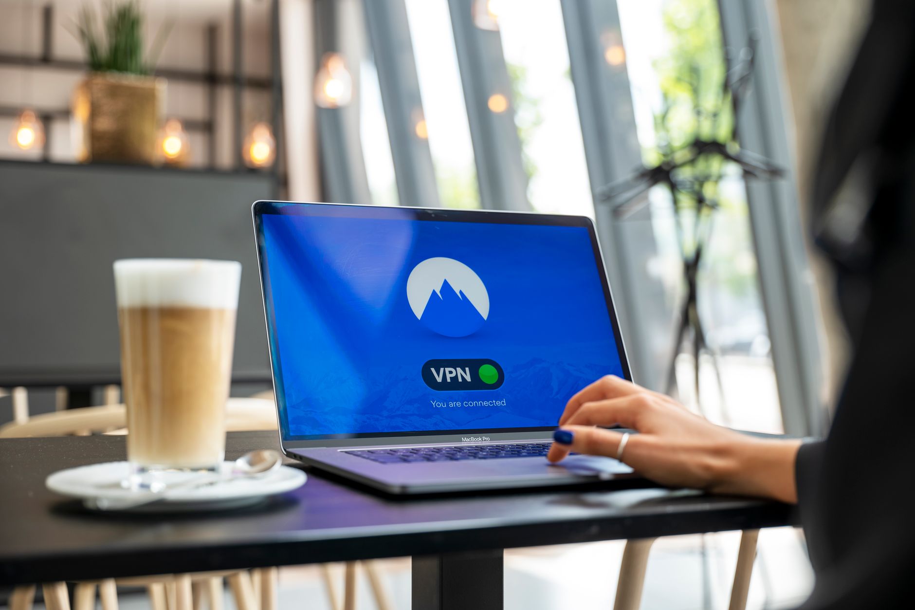 Person working on a laptop in a coffee shop using a public network securely